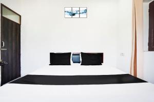 Un dormitorio con una cama blanca con almohadas negras. en Hotel O The Moon, en Bareilly