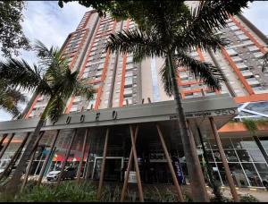 a tall building with palm trees in front of it at Studio Premium Zona Sul RP in Ribeirão Preto