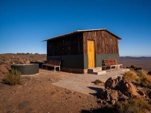 a building in the middle of the desert with two benches at Rooilande Guest Farm in Laingsburg +29 photos