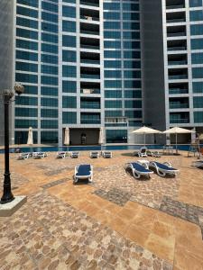 een terras met ligstoelen en parasols voor de gebouwen bij Luxury 2Bed Room sea view in Ajman 