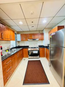 een keuken met houten kasten en een roestvrijstalen koelkast bij Luxury 2Bed Room sea view in Ajman 