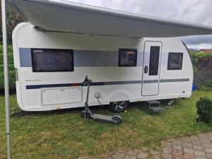 a white trailer parked on the grass in a field at Przyczepa ADORA nad morzem in Rumia