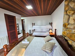 a bedroom with a large bed and a stone wall at Refúgio das Nuvens | by The Lodges in Campos do Jordão