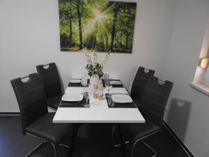 a white table with black chairs and a vase with flowers at Ferienwohnung Am Fischerhof 10a Wernigerode in Wernigerode