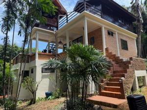 a house with stairs and palm trees in front of it at Bamboo Villa Koh Mak in Ko Mak