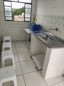 a kitchen with a sink and two stools at Aparecida Confortável Apartamento in Aparecida +10 photos