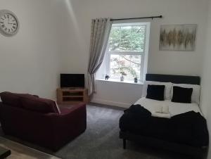 a bedroom with a bed and a couch and a window at Coach House Apartment - Sleeps 2 in Whitehaven