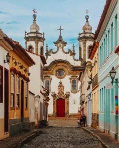 a church with a red door in a street at Loft Moderno- Centro Histórico in São João del Rei
