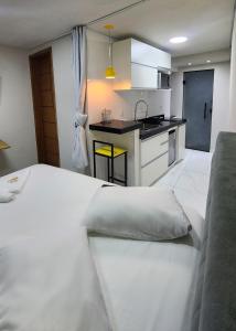 a large white bed in a room with a kitchen at Loft Moderno- Centro Histórico in São João del Rei