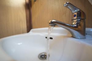 a bathroom sink with water running from a faucet at The fun boat - off grid - city centre - warm & cosy in Bath