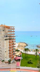 a building next to a beach with palm trees and the ocean at Atlantico Flamingo in Calpe