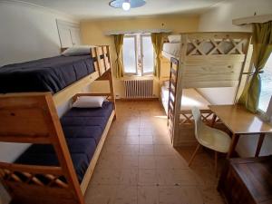 a bedroom with bunk beds and a desk and a table at Casa central hostel in San Carlos de Bariloche