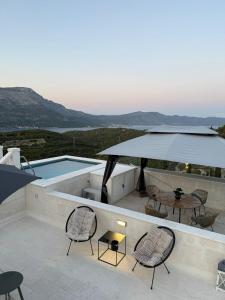 a patio with chairs and a table and a pool at Appartement Ellara Penthouse in Žrnovo