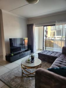a living room with a couch and a tv at 2 Bed Blyde Lagoon Getaway in Pretoria