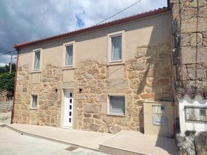 a large stone building with a white door at LolaPlayadeCarnota in Pedrafigueira