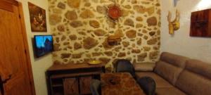 a living room with a couch and a stone wall at Casa abuelo Kalinas in Cazorla +16 photos