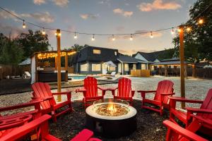 a group of red chairs sitting around a fire pit at Spacious Retreat with Pool & Hot Tub - 10 Minutes to Downtown in San Antonio