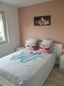 a bedroom with a white bed with pink and blue pillows at appartement avec beau jardin in Blois