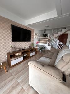 Casa com piscina em Bombinhas في بومبينهاس: غرفة معيشة مع أريكة وتلفزيون بشاشة مسطحة