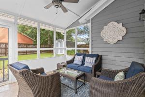 Coastal Haven 5 mins to Beach 15 mins to dtwn في تشارلستون: شاشة في الشرفة مع الكراسي وطاولة