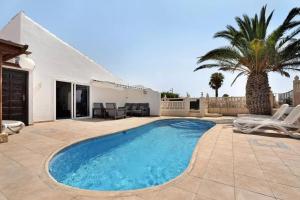 une piscine dans une cour avec des chaises et une maison dans l'établissement 3 Bed Villa - Sleeps 6 - Private Pool - Hot Tub- Parking - Wifi, à San Miguel de Abona