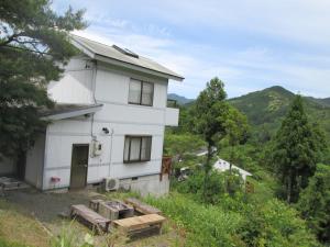 a white house on a hill with mountains in the background at Tentengo Shibu River - Vacation STAY 79348v in Ono