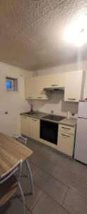 a kitchen with white cabinets and a table and a stove at Le petit Liancourtois, 1 bedroom in Liancourt