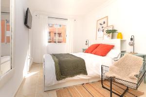 a white bedroom with a bed and a chair at Profithome-Punta Larga in Candelaria