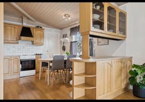 a kitchen with wooden cabinets and a table with chairs at KB - Villa sentrum Leknes in Vestvågøya