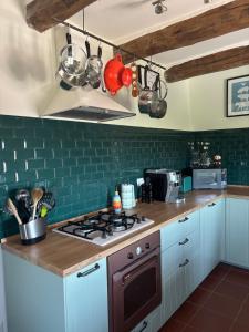 a kitchen with a stove top oven and green tiles at Casa Hemingway, Near Assisi in Armenzano +4 photos