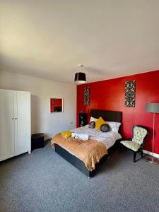 Willenhallにある#56 Stylish 4-Bed House Free Parking Near Shopsの赤い壁のベッドルーム(ベッド1台、椅子付)
