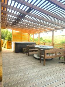 a patio with benches and a hot tub and a pergola at H25 Vendégház in Sóskút