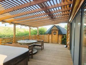 a wooden deck with a pergola and a table and bench at H25 Vendégház in Sóskút +24 photos