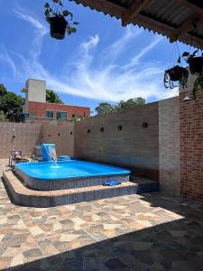 Casa com piscina em Bombinhas في بومبينهاس: حمام سباحة كبير في فناء مع جدار من الطوب