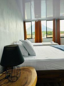 a bedroom with a bed with a lamp and a window at SUA Luxury Arenal Volcano View Apartments in Fortuna