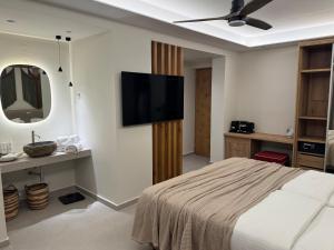 ein Schlafzimmer mit einem Bett und einem Flachbildfernseher in der Unterkunft Τhe Noverian Antama Organic Beach Resort Chania in Agia Marina