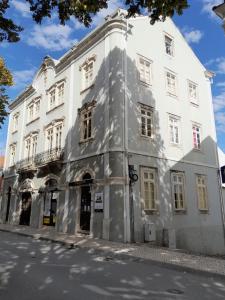 Un gran edificio blanco al costado de una calle. en António Augusto Apartment, en Coímbra