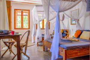a bedroom with a bed with blue drapes and a table at Kameleon Blue in Kizimkazi