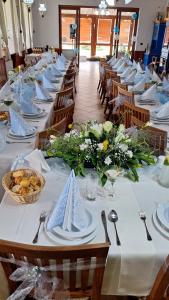 a long table with white plates and flowers on it at Penzión Petrov grunt in Košúty