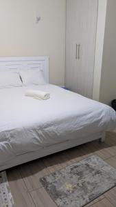 a bedroom with a bed with white sheets and a rug at Krystal suites in Juja