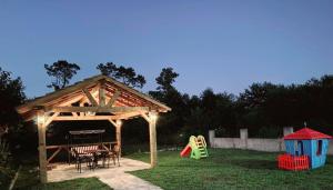 a wooden gazebo with a table and a playground at Villa MATE & Villa LUKA in Ureki