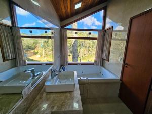 a bathroom with two sinks and a tub and two windows at Refúgio das Nuvens | by The Lodges in Campos do Jordão +66 photos
