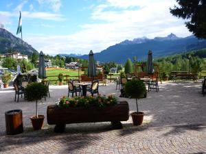 a patio with tables and chairs with flowers and umbrellas at Nord Hotel in Cortina dʼAmpezzo