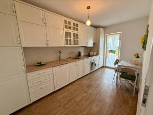a kitchen with white cabinets and a dining table at Vesel Fluturas Chic Apartment in Timişoara