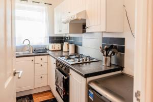 a kitchen with white cabinets and a stove top oven at 2 Bedroom Apartment Denton, suitable for professionals needing a peaceful work environment in Manchester