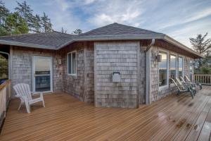 eine Holzterrasse mit Stühlen und ein Haus in der Unterkunft Cape View Escape in Pacific City
