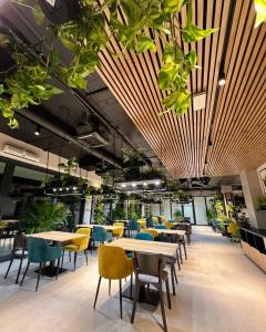 a cafeteria with tables and chairs and plants at Baltic Waves Resort & SPA Międzyzdroje 2 in Międzyzdroje