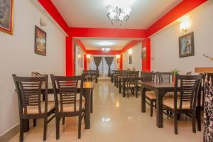 comedor con paredes rojas y mesas y sillas de madera en Hotel O Park Inn, en Bhurtuk