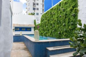 a swimming pool with a green hedge on a building at Ocean Park 1BD 1BA Pool Walk to beach -Santorini4 in San Juan +14 photos