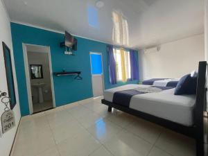 ein Schlafzimmer mit einem Bett und einer blauen Wand in der Unterkunft Hotel Cayena in Tame